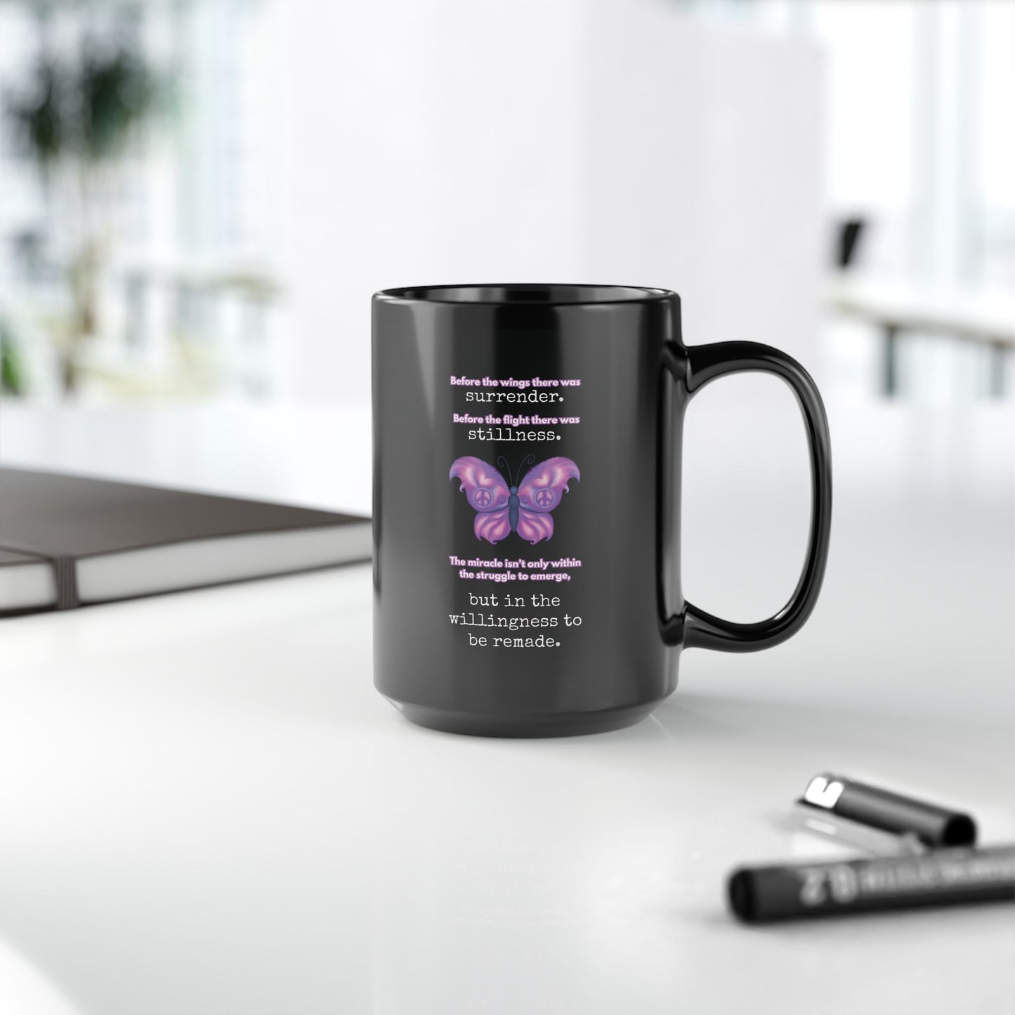Black mug with butterfly design and text on a white surface