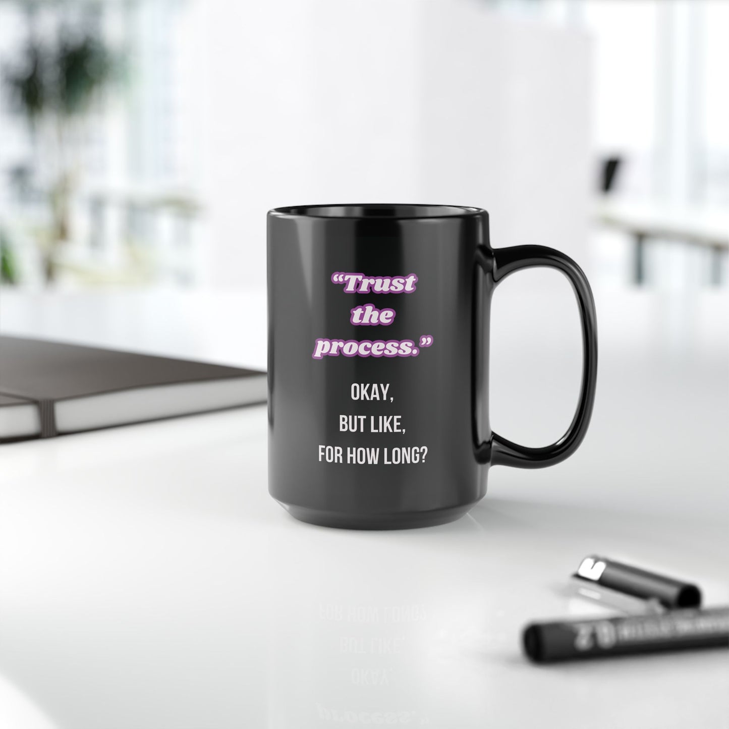 Black mug with motivational quote on a desk with office items