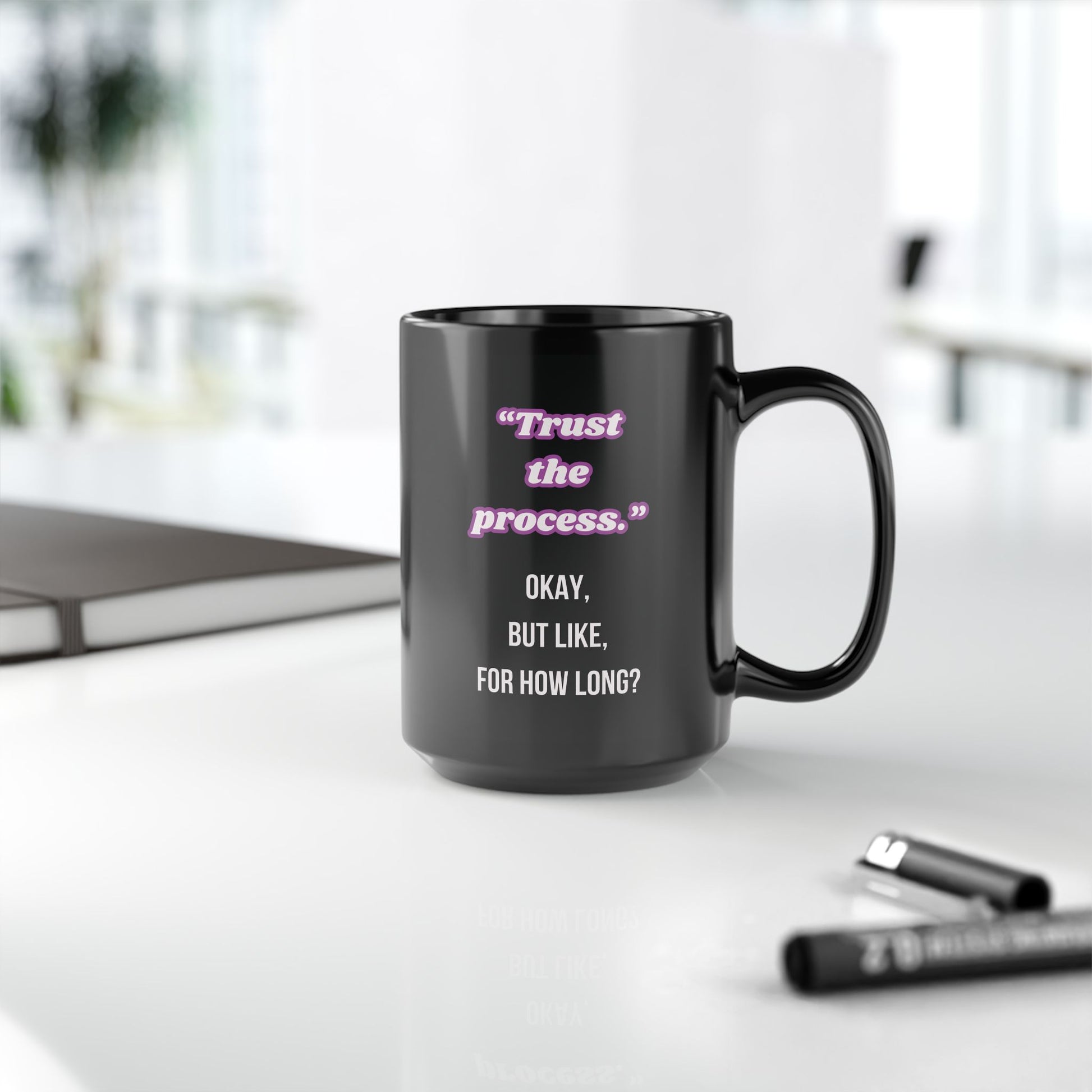 Black mug with motivational quote on a desk with office items