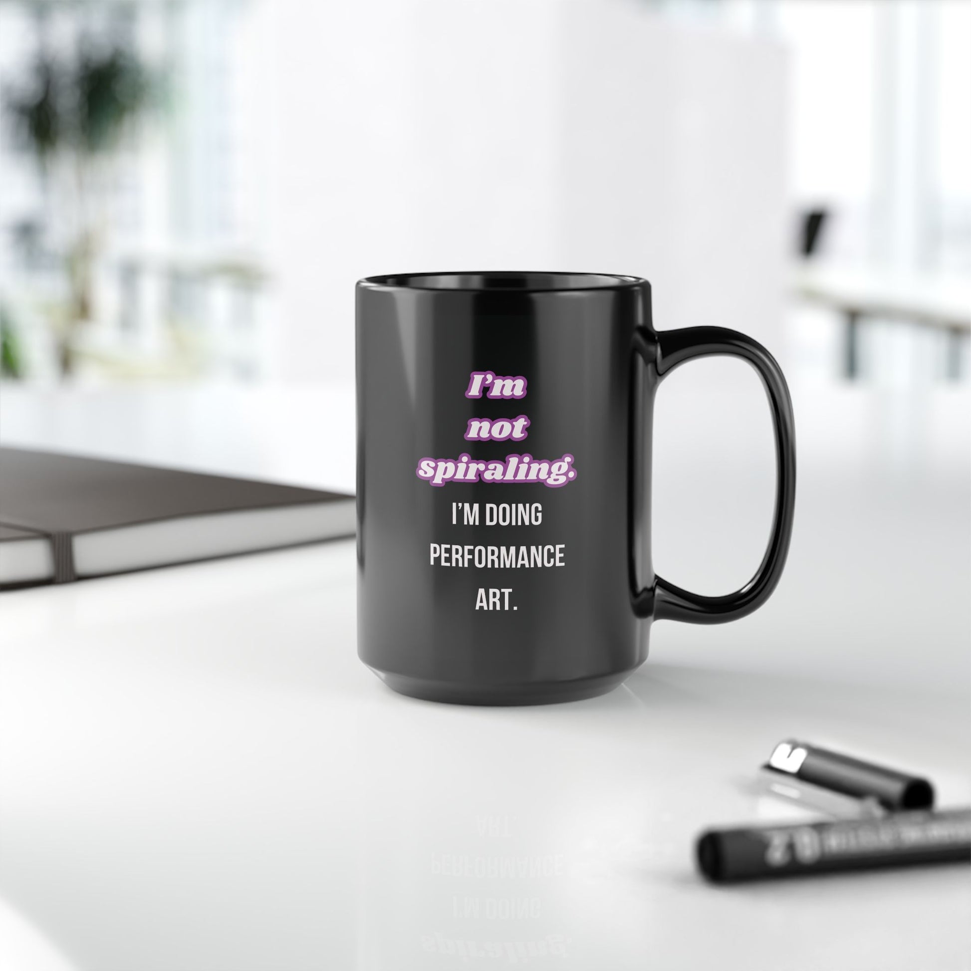 Black mug with humorous text on a desk with office items.