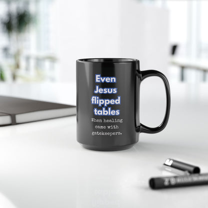 Black mug with humorous text on a white surface with office items.
