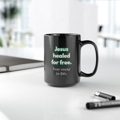 Black mug with text on a white surface with office items