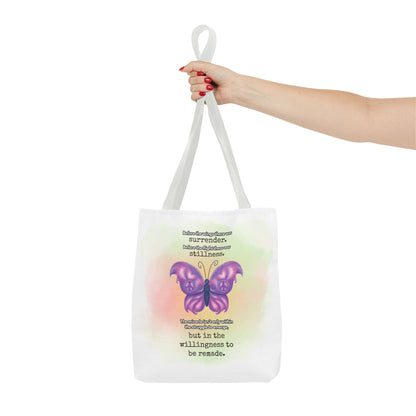 Tote bag with a butterfly design and text held by a hand on a white and background.