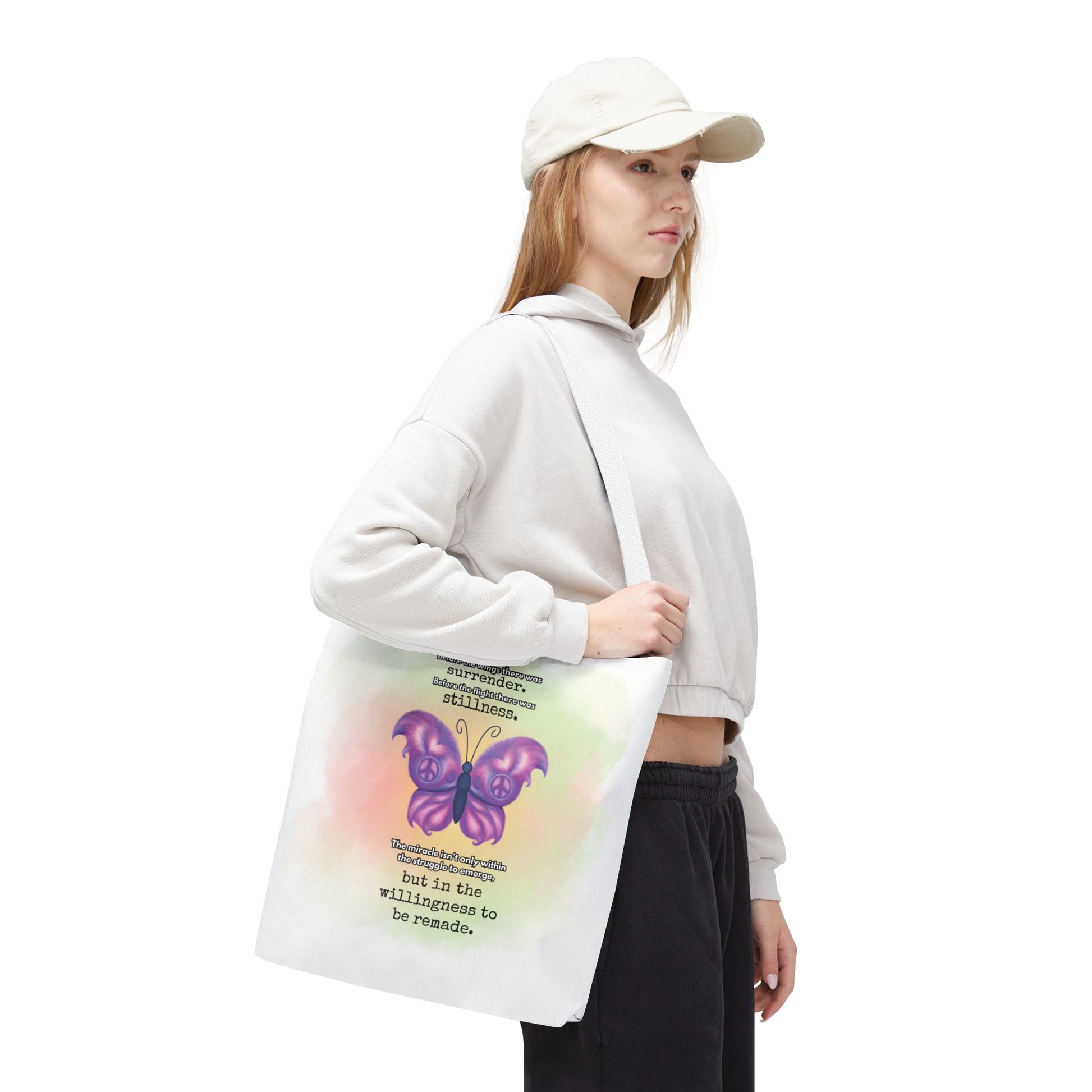 Person holding a tote bag with a butterfly design and text on a white background