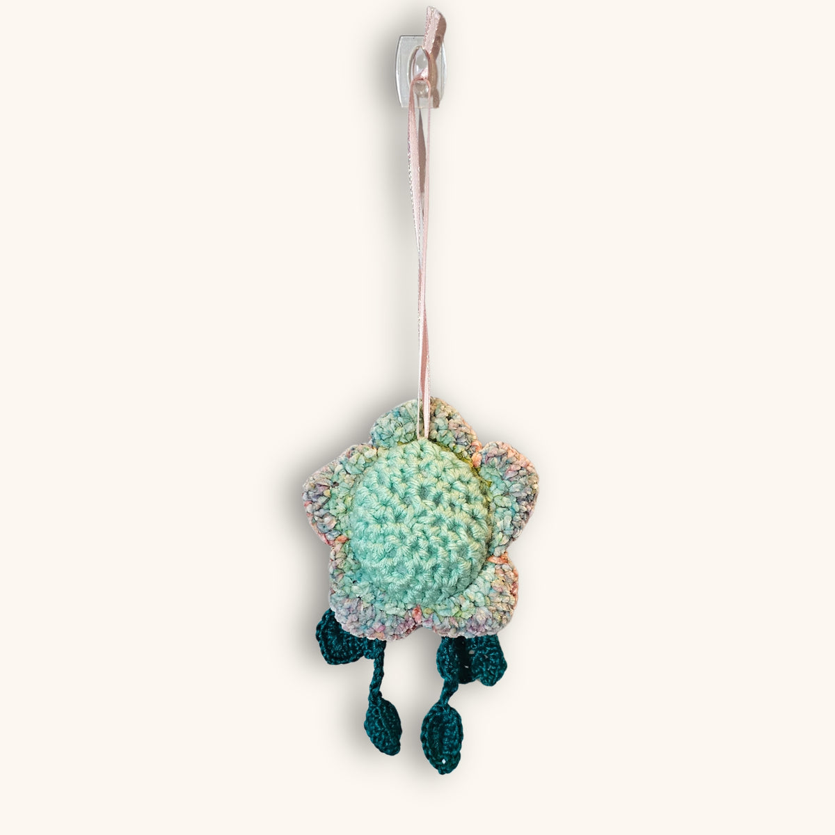 Back view of Floyd Flower Boy showing the handmade pastel crochet flower, mint green center, pink hanging ribbon, and dangling teal legs.