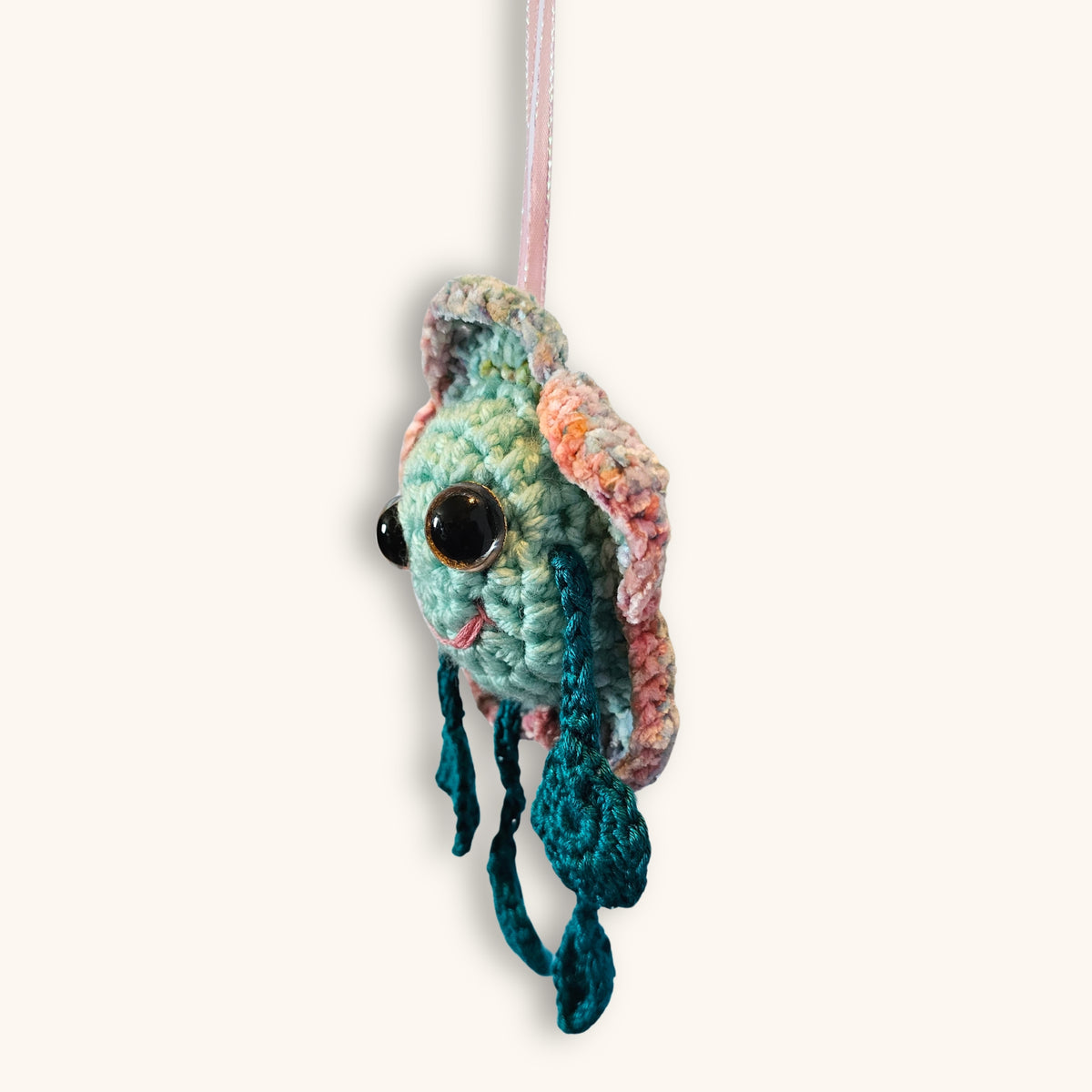 Side view of Floyd Flower Boy showing the layered crochet flower petals, raised round face, hanging ribbon, and teal limbs.