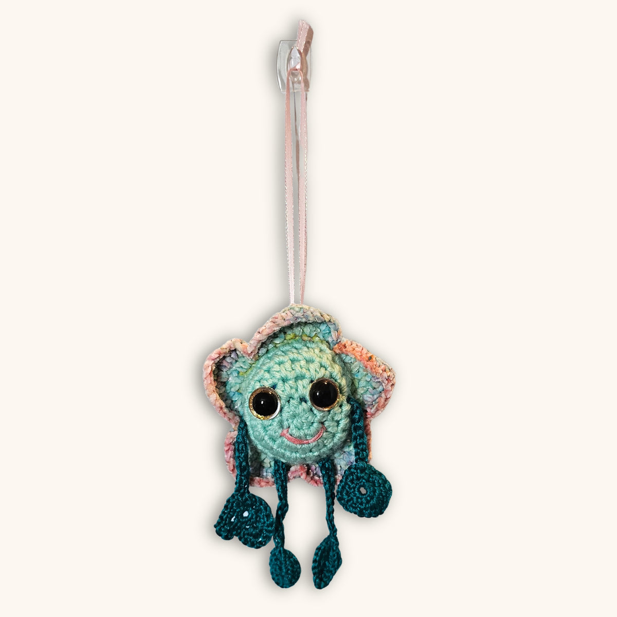 Floyd Flower Boy hanging by his pink ribbon, showing the full handmade crochet flower keepsake with dangling arms and legs.
