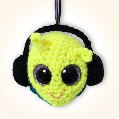 Groovy Gus handmade crochet decorative keepsake with a neon yellow-green face, black side details, purple-rimmed sparkly eyes, pink smile, and black hanging ribbon.