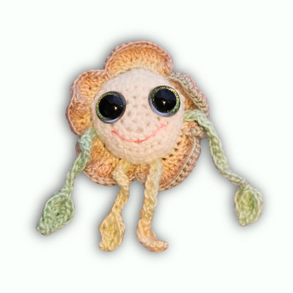 A handmade crocheted flower dalmatian plush toy with large black eyes, a pink stitched smile, and green leaf-shaped limbs, shown against a plain white background.
