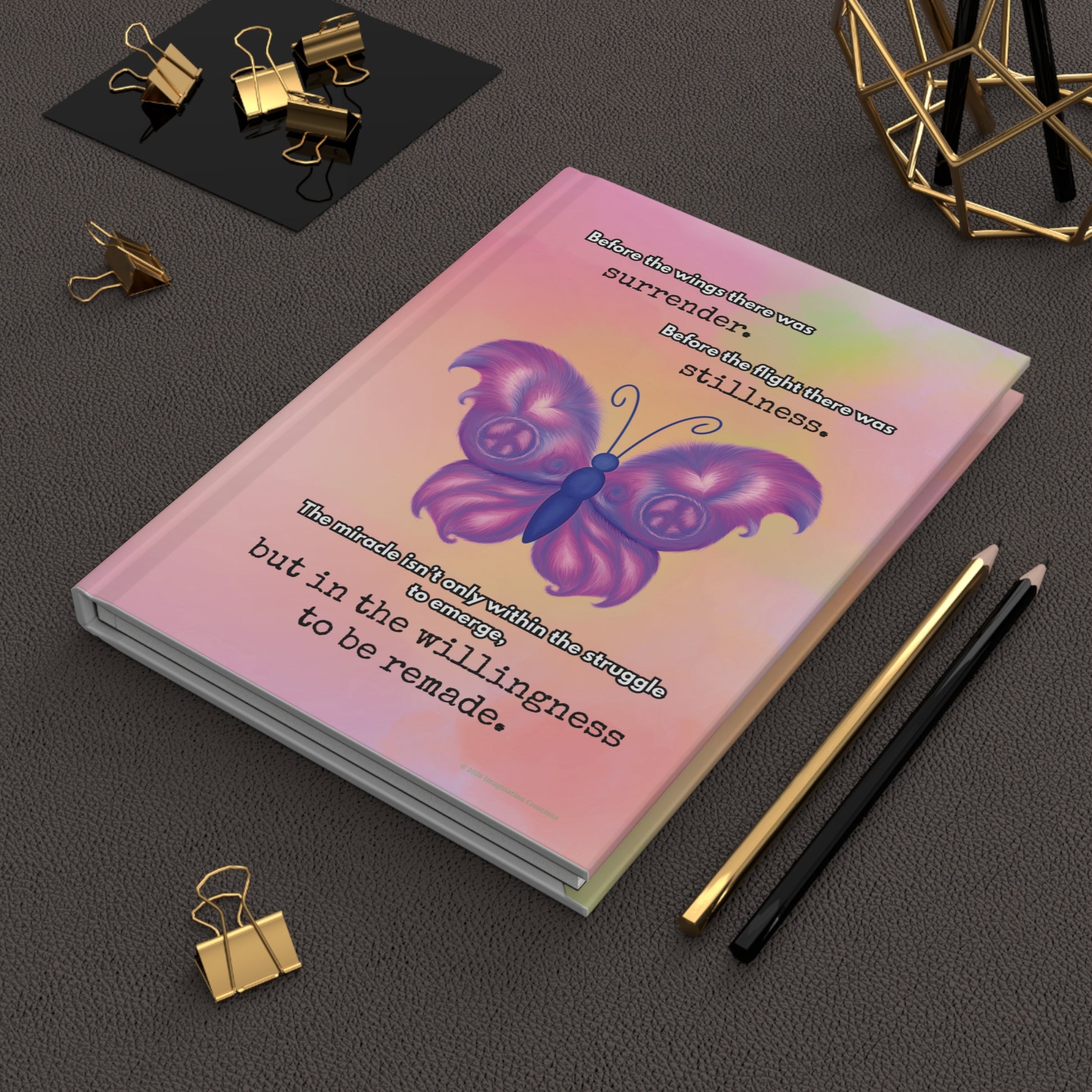 Notebook with a purple butterfly design on a dark surface with office supplies.