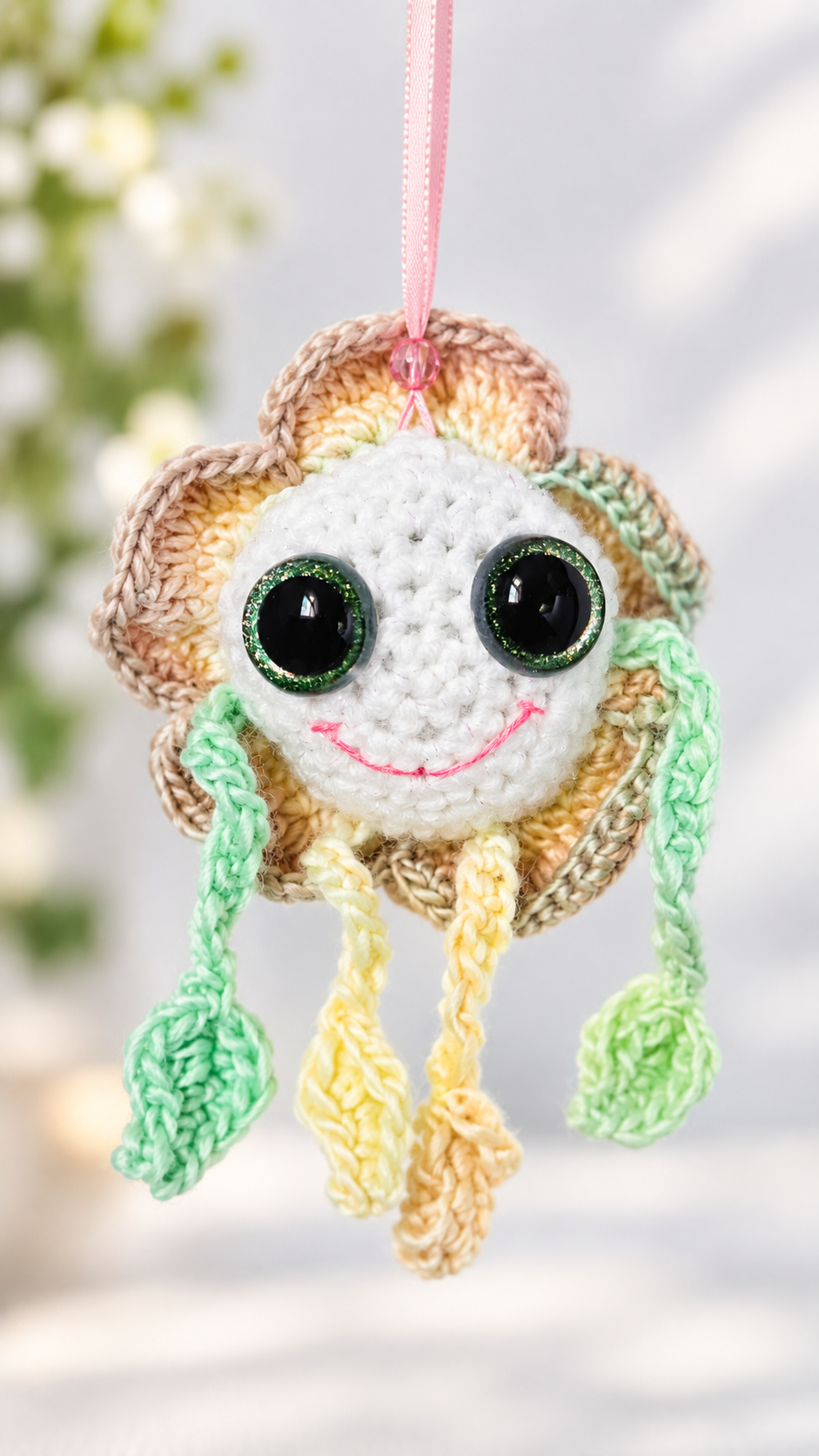 Front view of Mellow Marigold crochet flower ornament suspended by a pink ribbon.
