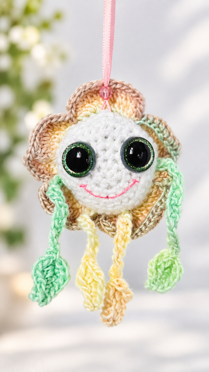 Front view of Mellow Marigold crochet flower ornament suspended by a pink ribbon.