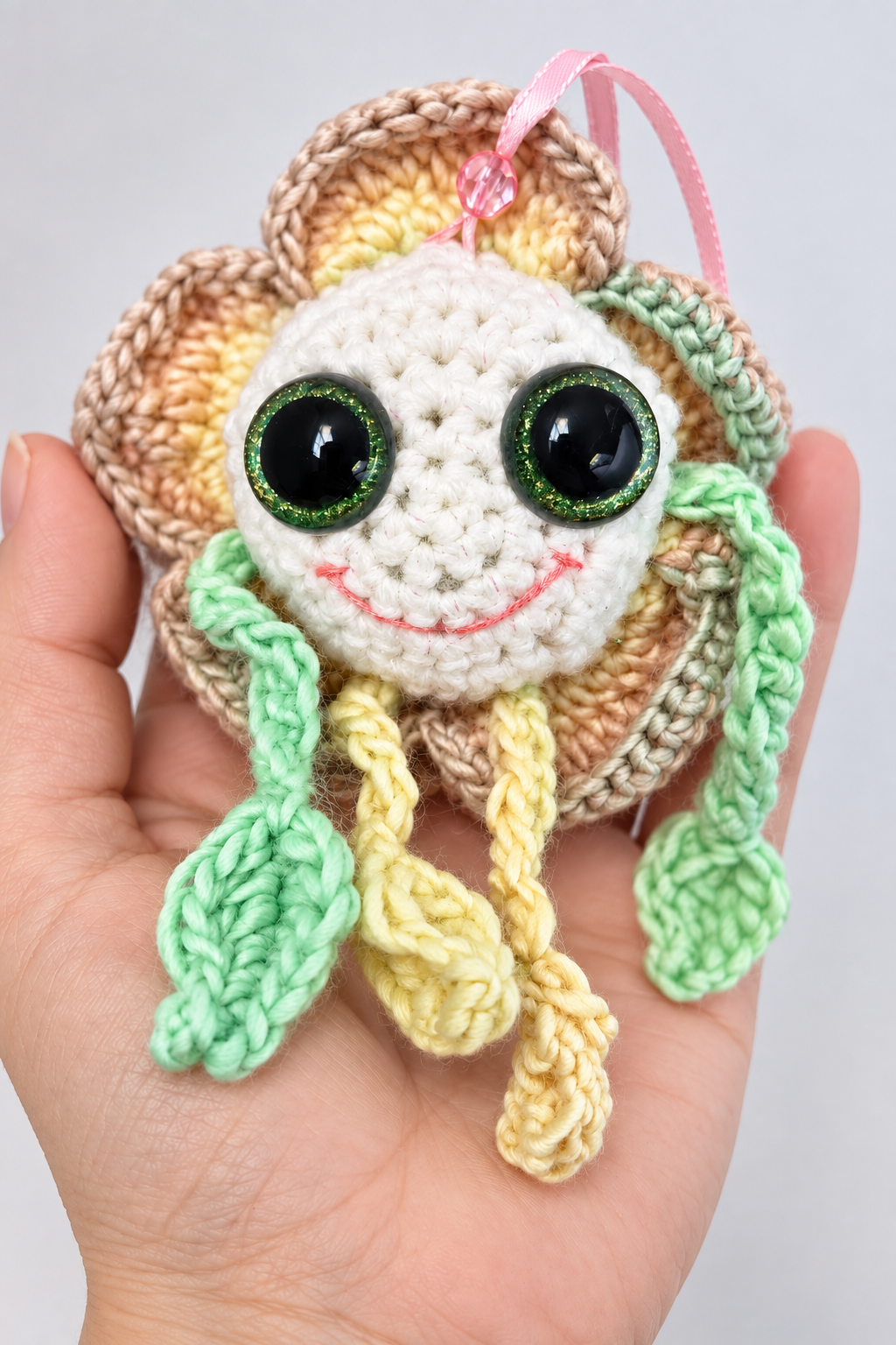 Hand holding Mellow Marigold handmade crochet flower plush in an open palm to display size and scale.
