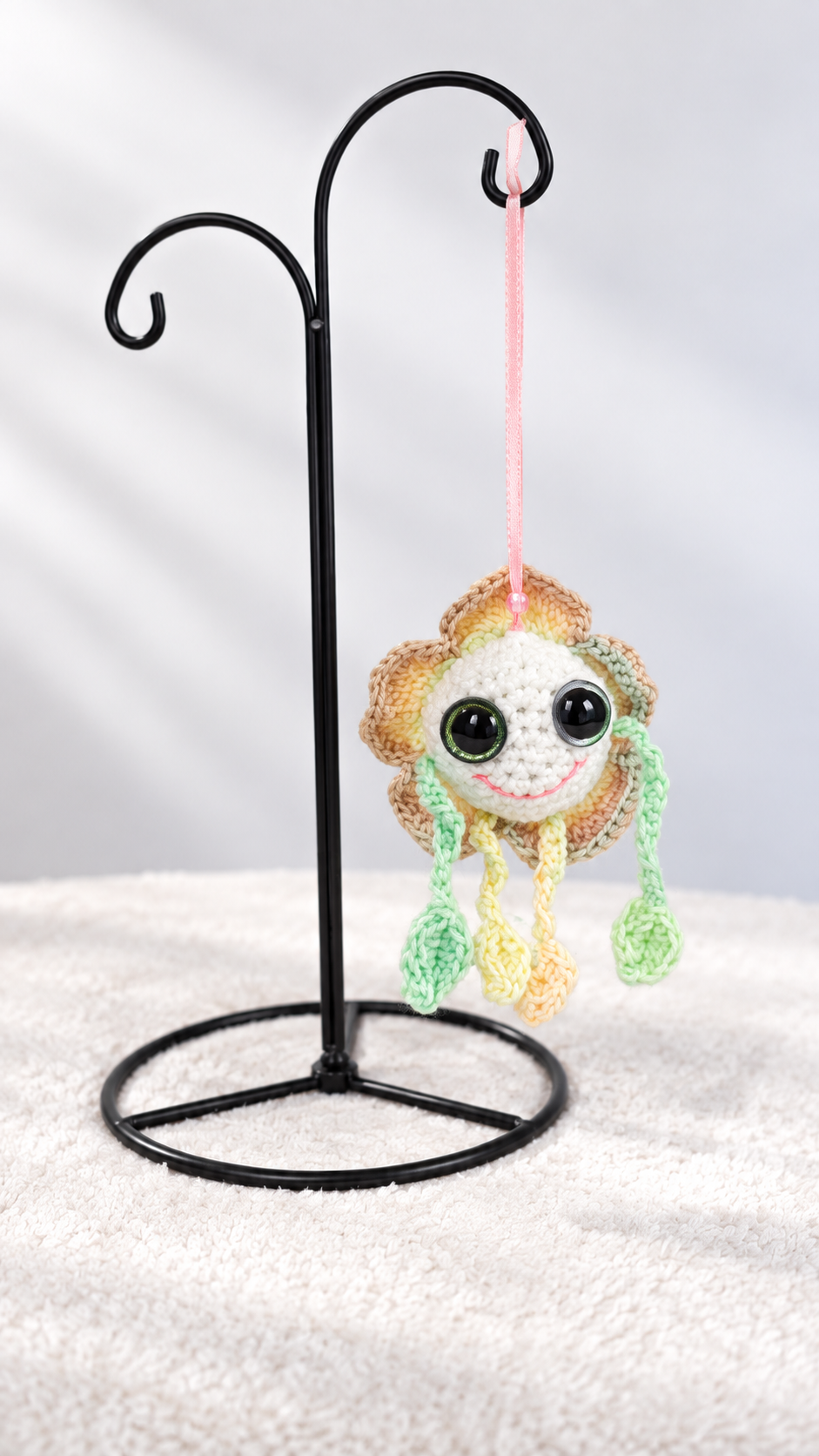 Mellow Marigold hanging by a pink ribbon from a black metal ornament display stand.