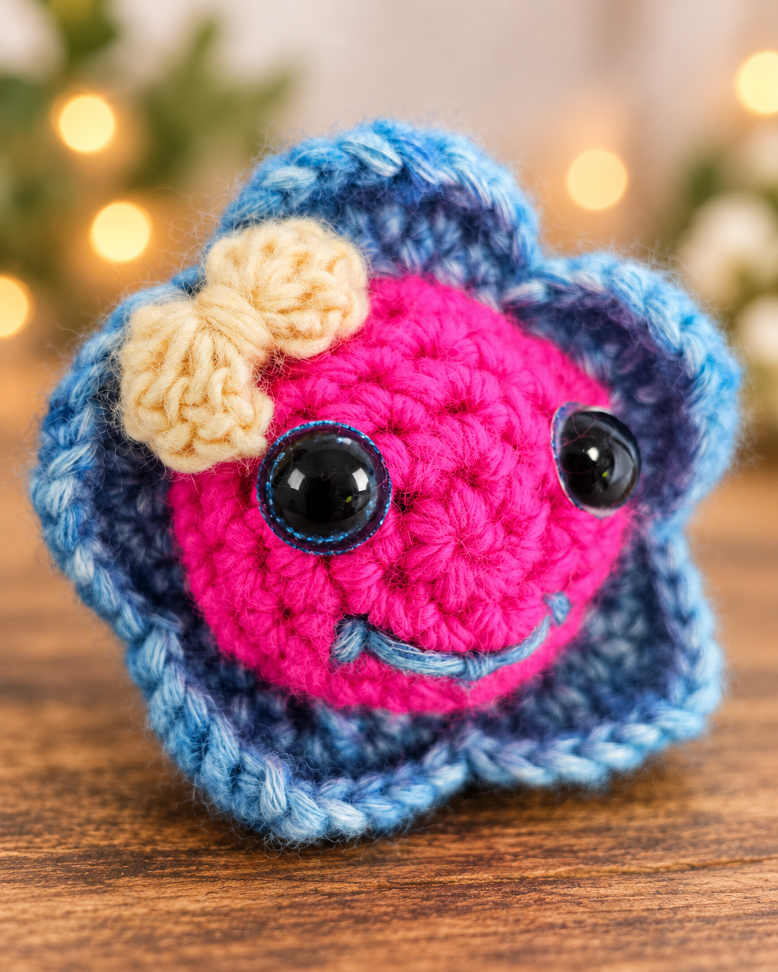 Close up view of Pinky Bluefin showing her bright pink crochet face, yellow bow, black sparkly eyes, and blue fin border.