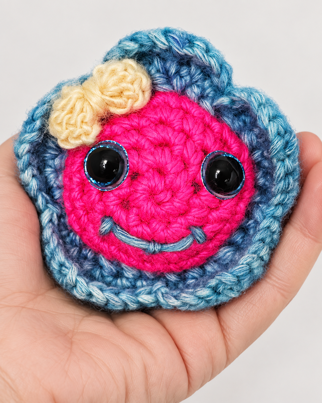 Hand holding Pinky Bluefin handmade crochet fish plush in an open palm to display size and scale.