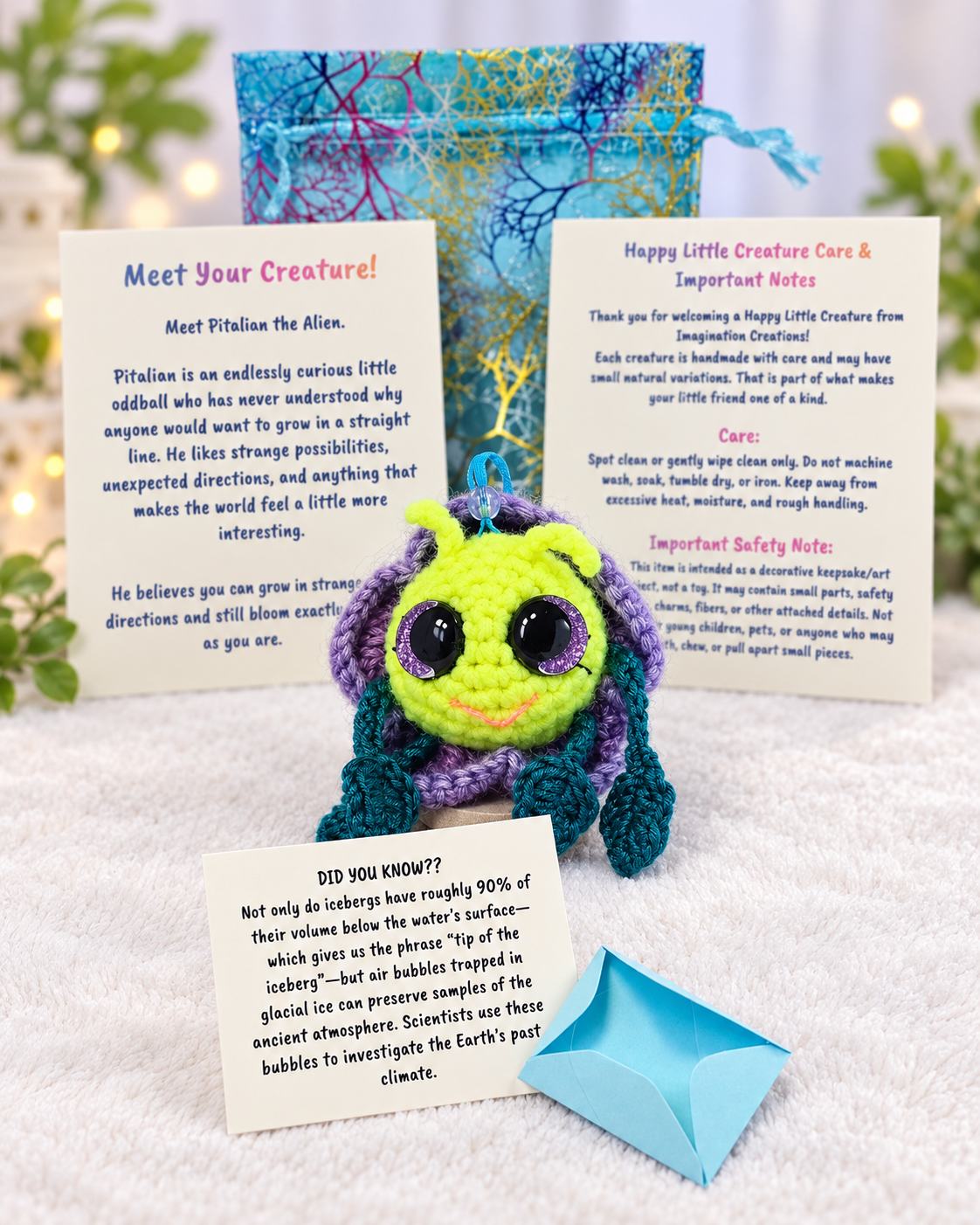 Unboxing set for Pitalian the alien showing handmade crochet creature, mystery message envelope, printed card, and pouch.