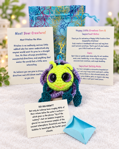 Unboxing set for Pitalian the alien showing handmade crochet creature, mystery message envelope, printed card, and pouch.