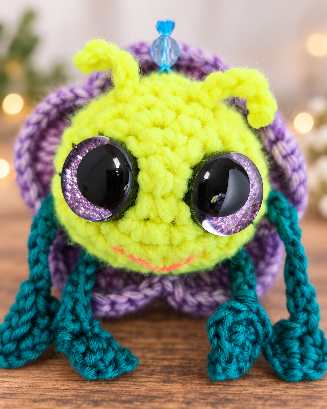 Close up view of Pitalian the alien's neon yellow crochet face, sparkly black safety eyes, and lavender flower petals.