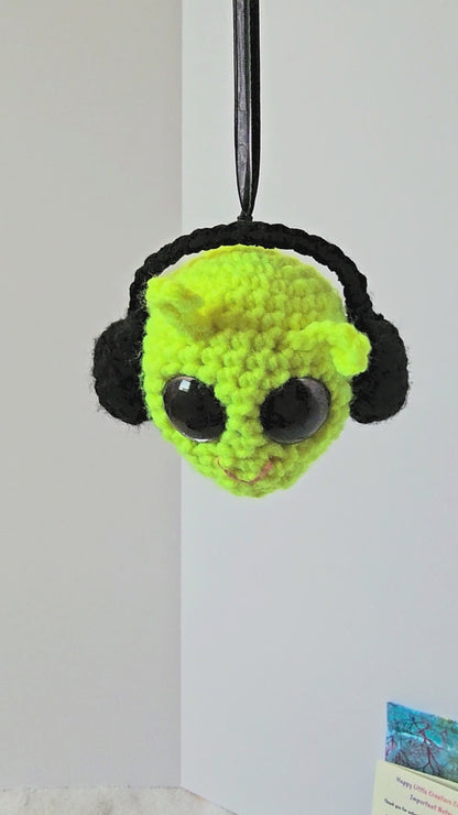 360-degree view of Groovy Gus, a handmade crochet decorative keepsake with a neon yellow-green face, black side details, purple-rimmed sparkly eyes, colorful layered back, and lavender peace sign.